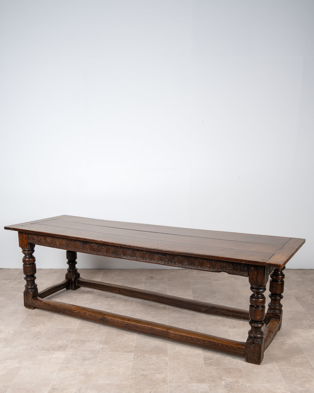 Antique English oak refectory dining table with plank top, carved frieze and turned legs