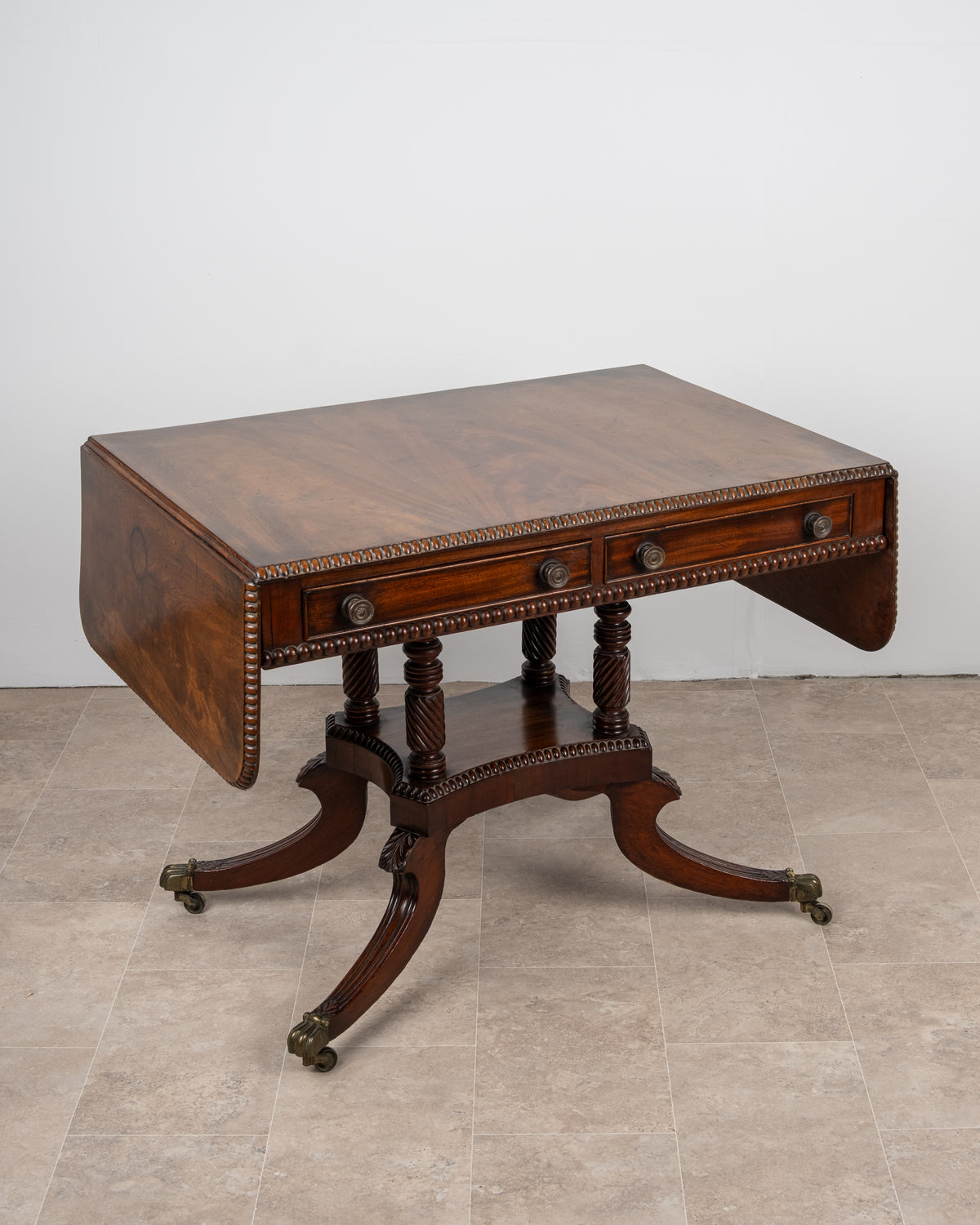 Antique Regency mahogany sofa table with drop leaves lowered and carved platform base