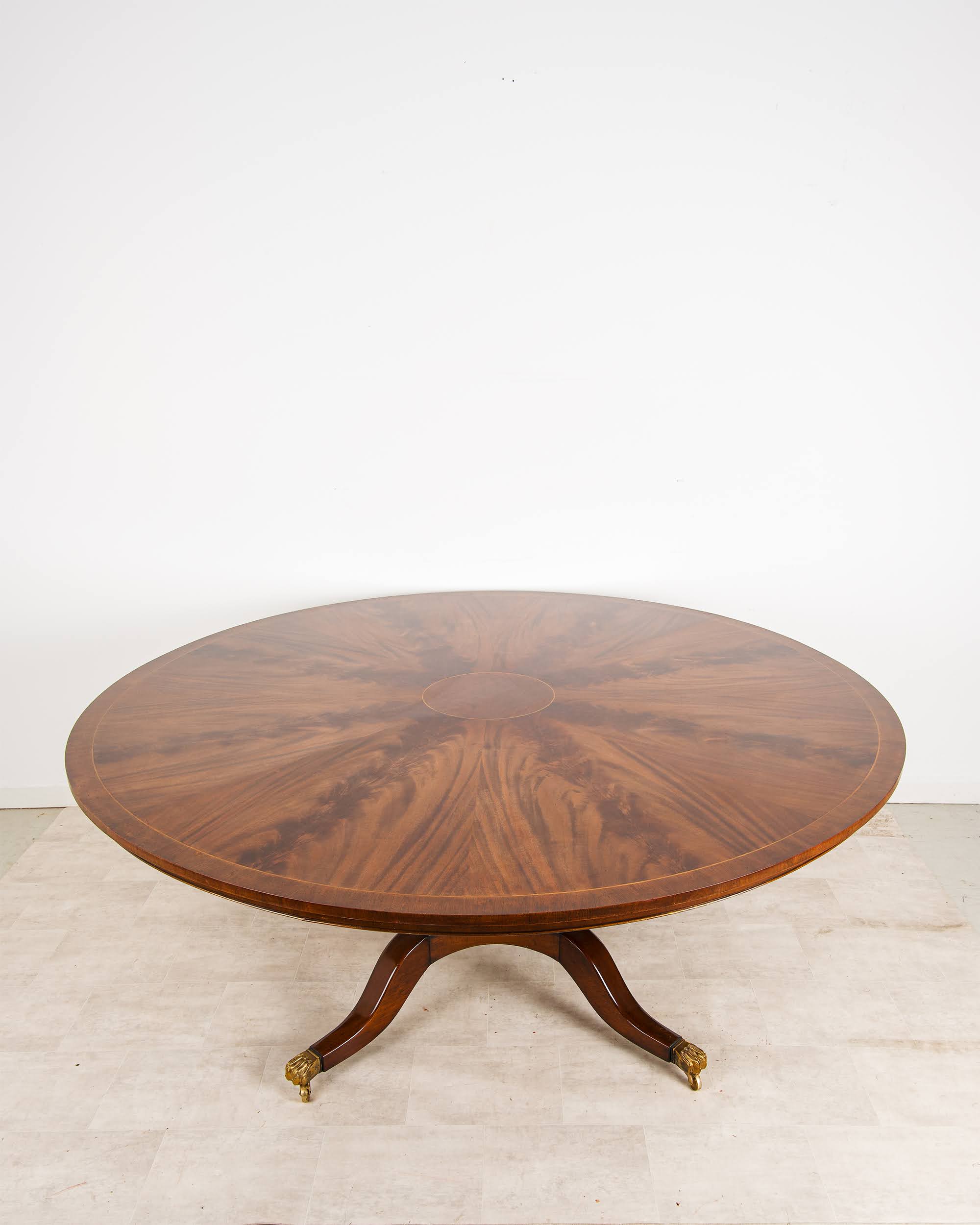 Large Regency style circular flame mahogany dining table with lion paw castors